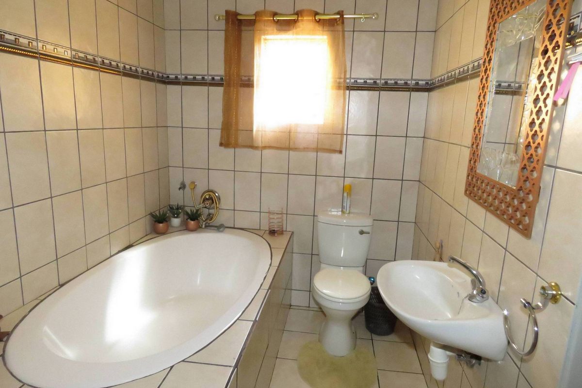 A compact bathroom featuring a built-in bathtub, a standard toilet, and a wall-mounted basin with full-height wall tiling.