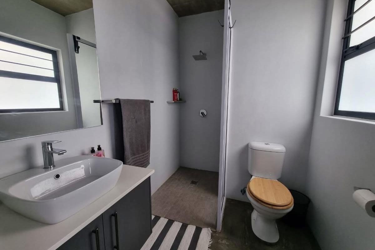 Modern bathroom featuring a vessel sink vanity, walk-in shower with concrete ceiling, and contemporary fixtures.