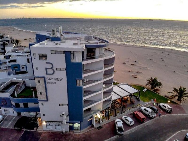 Aerial view of the Bay View Resort apartment building, showcasing its beachfront location, multi-level balconies, and proximity to the coastline.