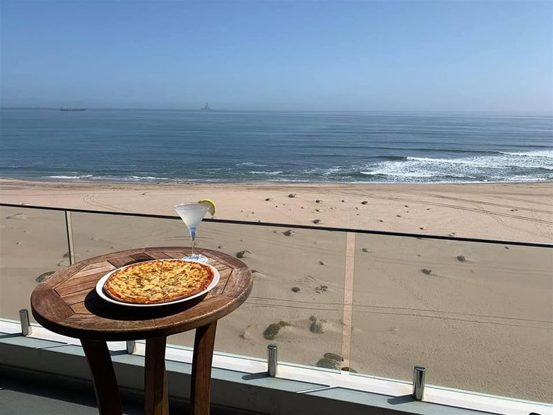 A balcony featuring a modern glass balustrade, offering expansive, unobstructed views of the beach and ocean.