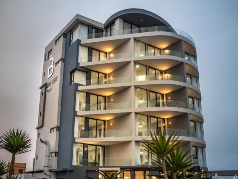 Modern multi-story apartment building featuring curved balconies with glass balustrades and contemporary architectural design.