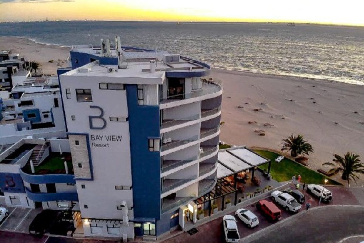 Aerial view of the Bay View Resort apartment building, showcasing its beachfront location, multi-level balconies, and proximity to the coastline.