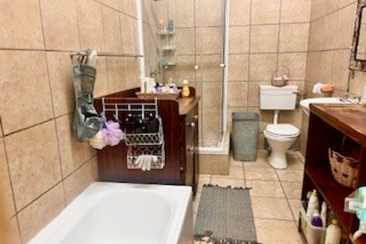 A functional bathroom featuring a built-in bathtub, a separate glass-enclosed shower, a toilet, and a vanity unit with tiled walls and flooring.