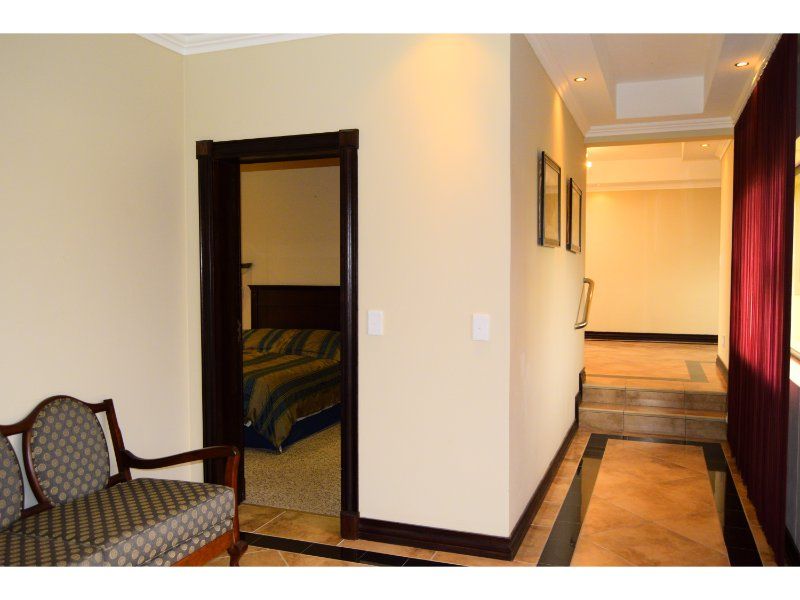 A tiled hallway featuring recessed ceiling lighting and a step transition leading to an adjacent living area, with a doorway opening into a bedroom.