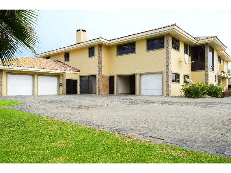 A spacious front exterior view of a multi-level house featuring a triple garage, extensive paved driveway, and stone-accented facade.