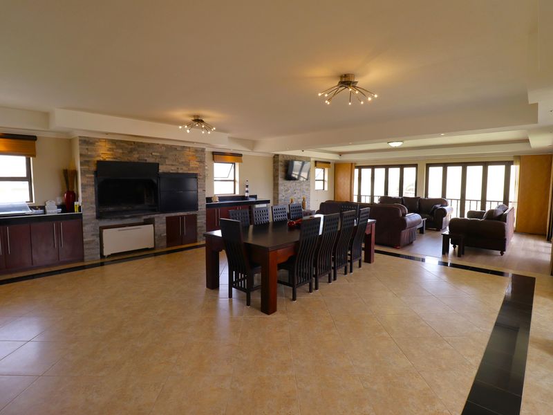 Spacious open-plan living and dining area featuring a built-in braai, stone-clad feature wall, tiled floors, and large sliding doors leading to the exterior.