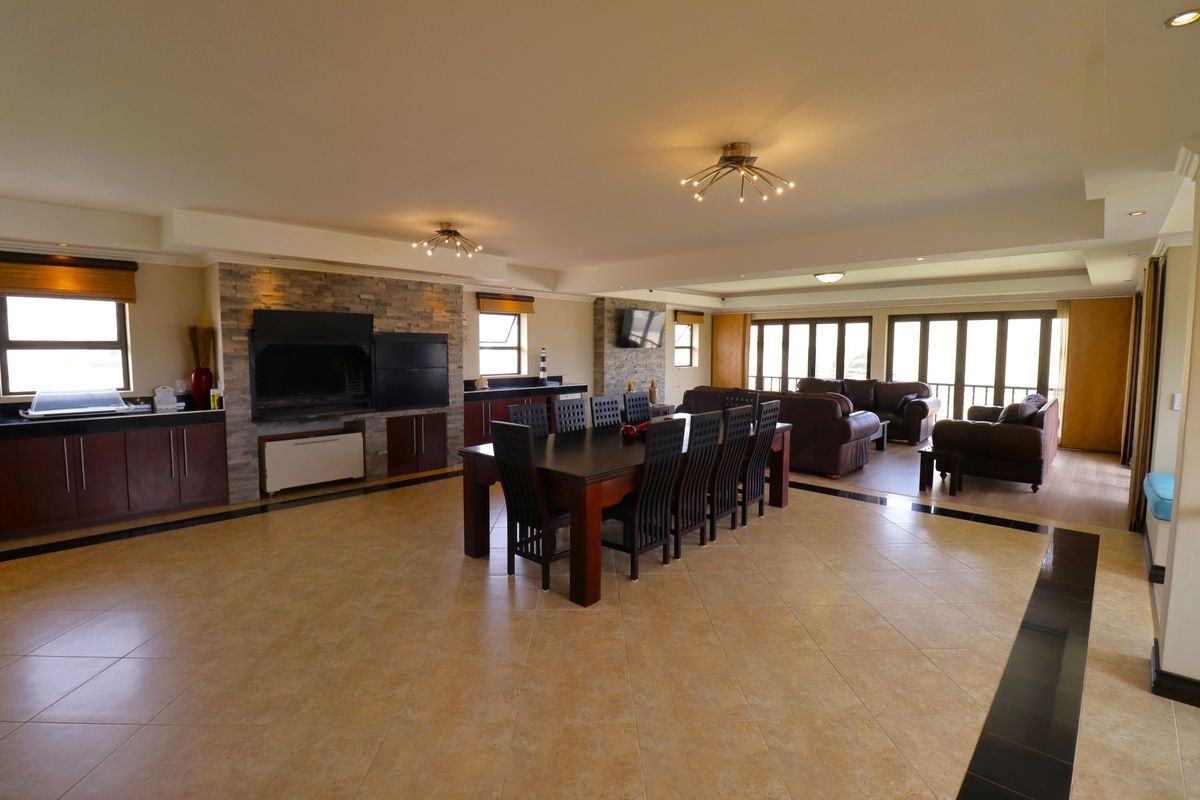 Spacious open-plan living and dining area featuring a built-in braai, stone-clad feature wall, tiled floors, and large sliding doors leading to the exterior.