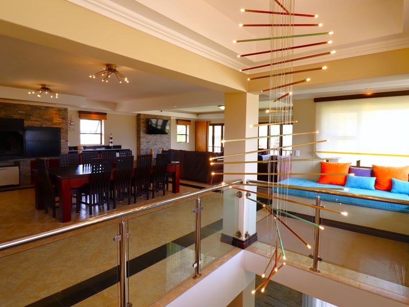 Spacious open-plan living and dining area featuring a stone fireplace, glass balustrade, and a built-in window seat with modern lighting.