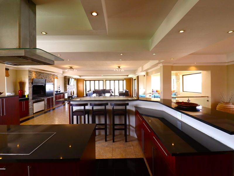 Spacious open-plan kitchen and living area featuring modern cabinetry, granite countertops, a built-in fireplace, and recessed lighting throughout.