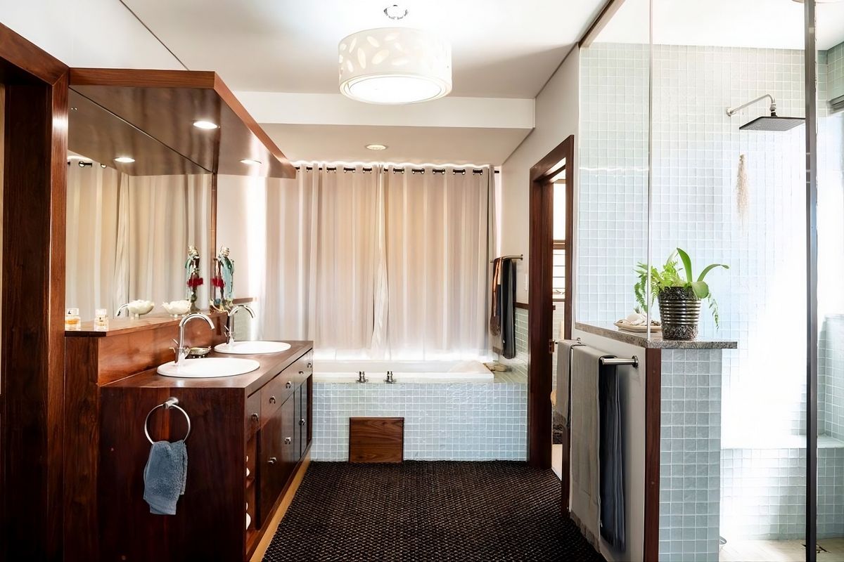 A well-appointed bathroom featuring a double vanity with wooden cabinetry, a built-in bathtub, and a separate glass-enclosed shower with mosaic tiling.
