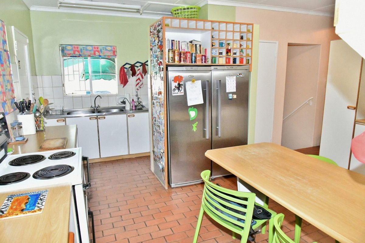 A functional kitchen featuring tiled flooring, white cabinetry, a double sink, and a built-in storage unit, offering potential for modernization.