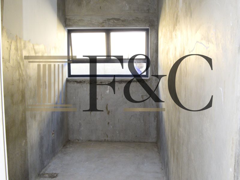 An unfinished utility space featuring raw concrete walls, exposed flooring, and an aluminium window frame, currently in a shell condition awaiting final finishes.