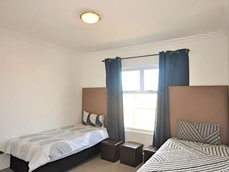 A functional bedroom featuring tiled flooring, a central ceiling light, and a window with curtain rod.