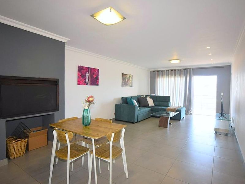 Spacious open-plan living and dining area featuring tiled floors, a built-in fireplace, and direct access to a balcony through sliding glass doors.