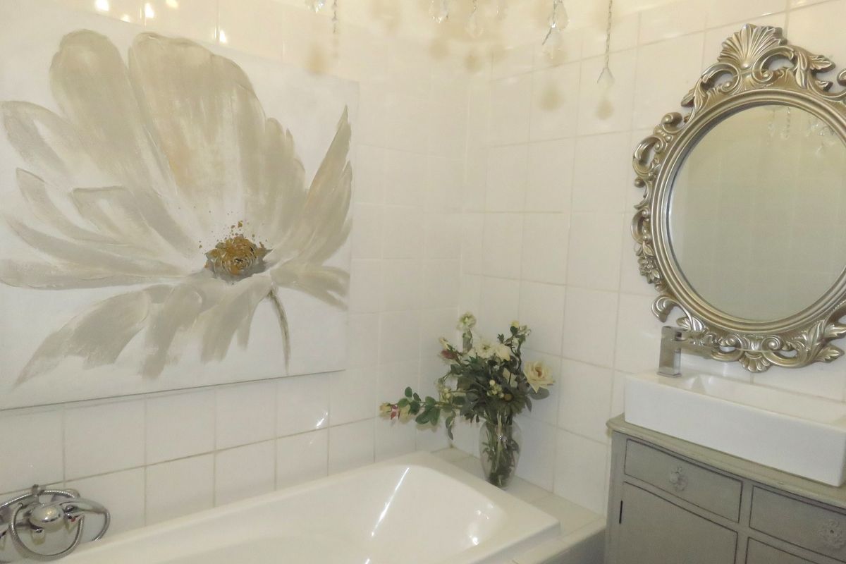 A bathroom featuring a built-in bathtub, a vanity cabinet with a vessel sink, and wall-mounted tiling.