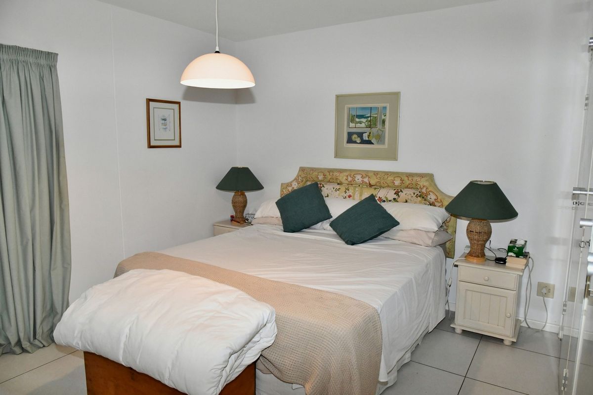 A functional bedroom featuring tiled flooring, neutral walls, and a central pendant light fixture.