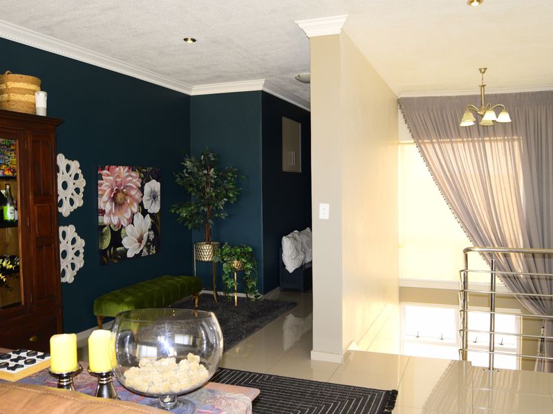 A well-maintained living area featuring tiled floors, crown molding, and a modern stainless steel balustrade overlooking the lower level.
