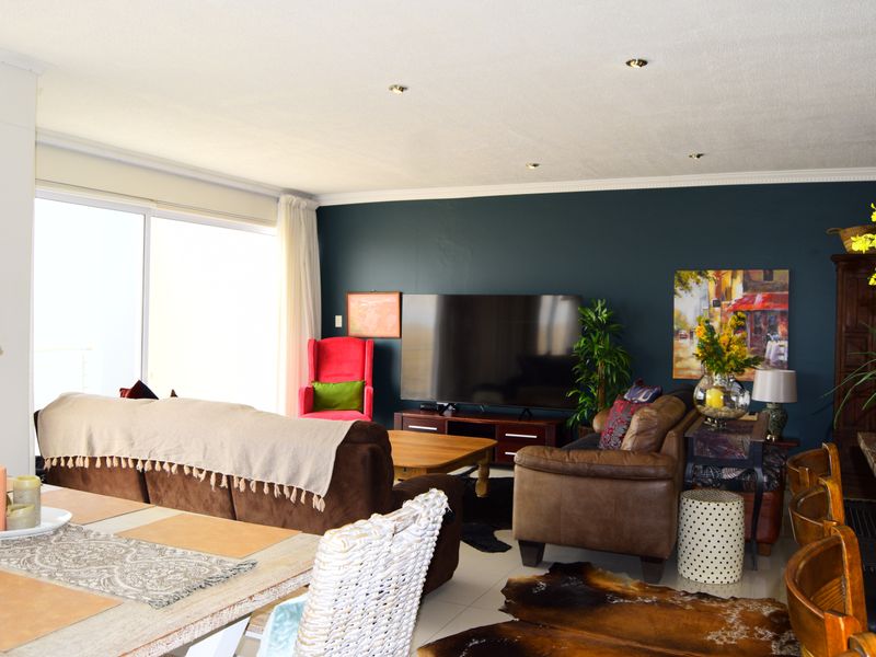 Spacious open-plan living area featuring tiled flooring, recessed downlighting, and large sliding glass doors that provide ample natural light.