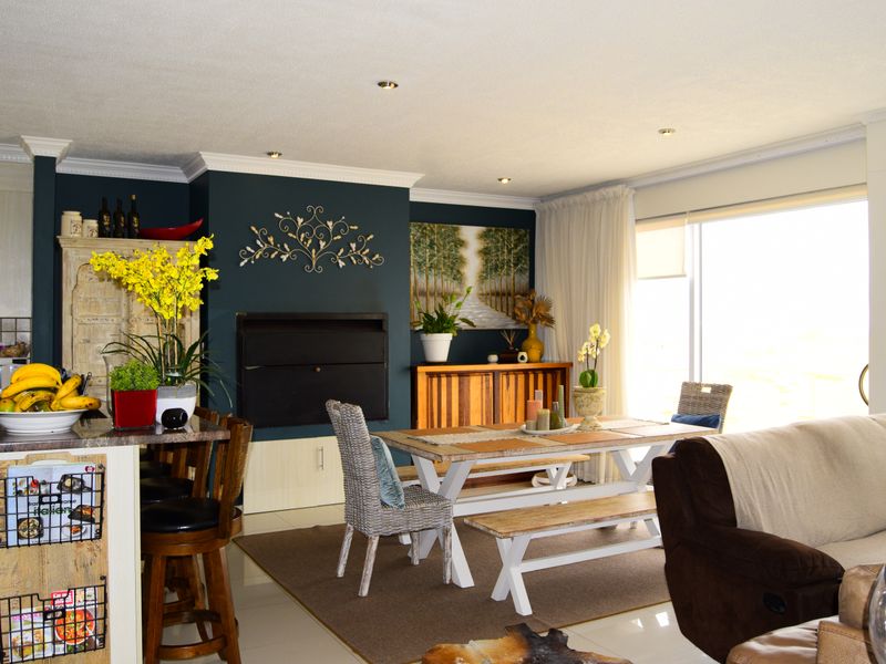 An open-plan living and dining area featuring tiled floors, recessed lighting, crown molding, and a built-in fireplace with a dark accent wall.