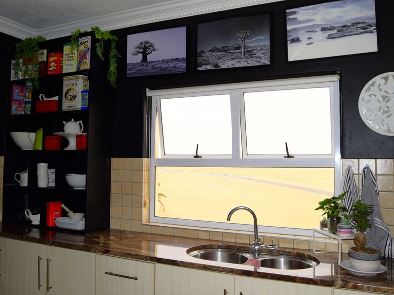 A kitchen area featuring built-in cabinetry, granite countertops, a double bowl stainless steel sink with mixer tap, and tiled splashback.