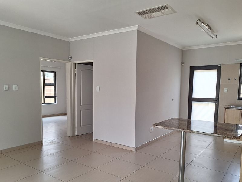 Open plan living area featuring neutral tiled flooring, a breakfast bar, and direct access to adjacent rooms.