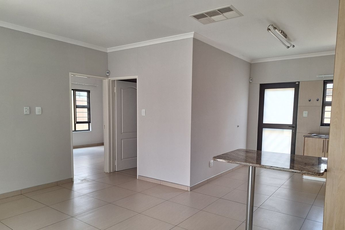 Open plan living area featuring neutral tiled flooring, a breakfast bar, and direct access to adjacent rooms.