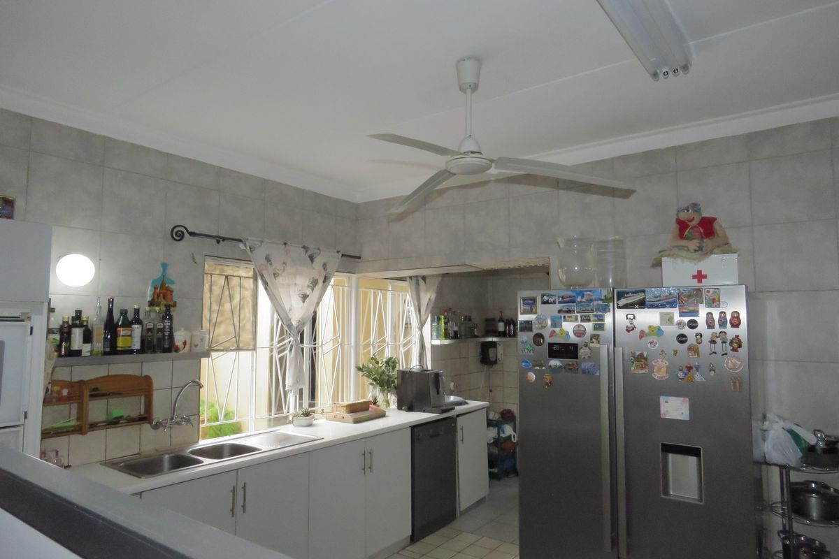 A functional kitchen featuring tiled walls, double bowl sink, built-in cabinetry, and a ceiling fan, providing a practical workspace with natural light.