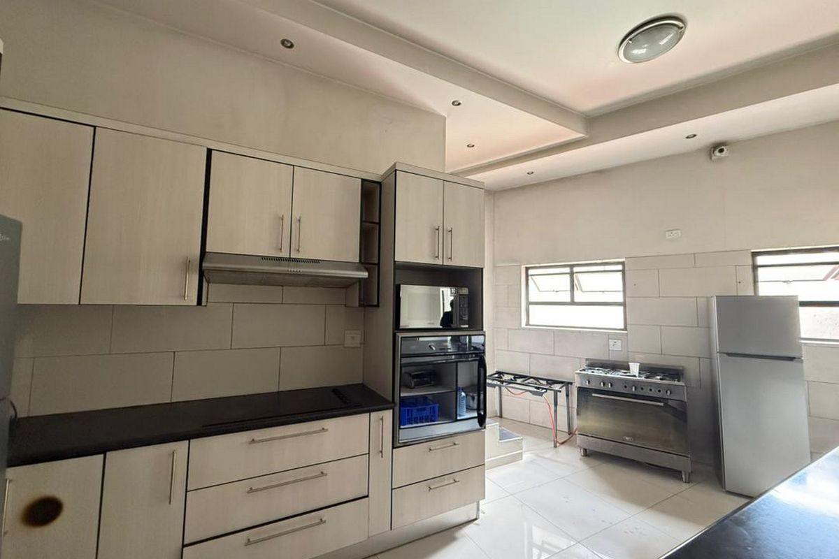 A functional kitchen featuring light-toned built-in cabinetry, integrated appliances, tiled backsplash, and recessed ceiling lighting.