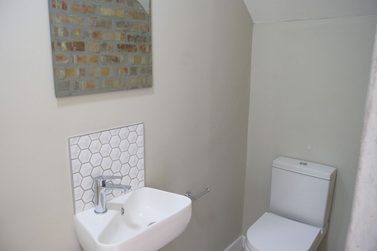 A compact guest bathroom featuring a modern wall-mounted basin with a stylish hexagonal tile splashback and a standard toilet suite.