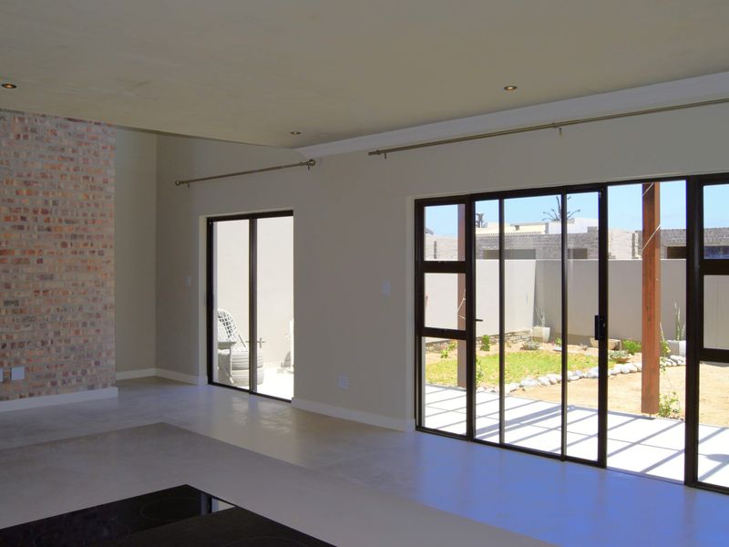 Spacious open-plan living area featuring an exposed brick wall, tiled flooring, and large sliding glass doors providing direct access to the rear garden.