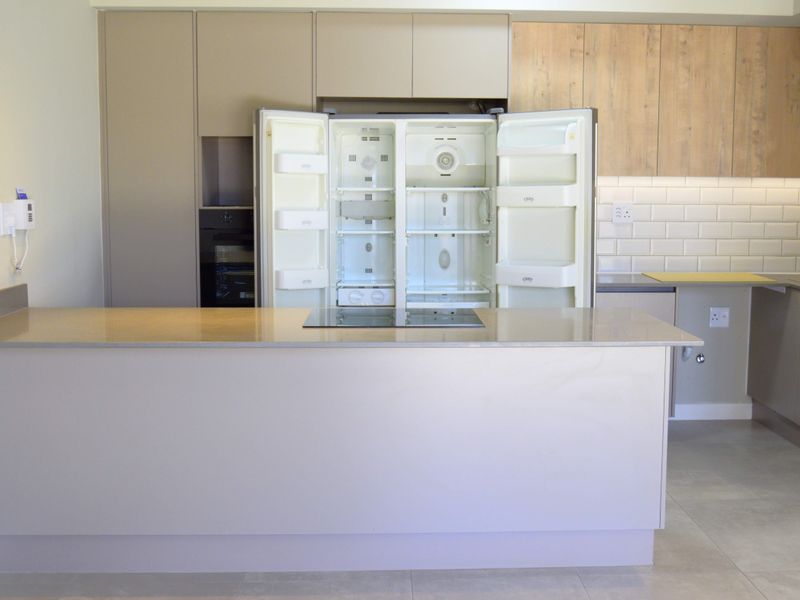 Modern kitchen featuring a central island with induction hob, quartz countertops, subway tile backsplash, and integrated cabinetry with a built-in oven.