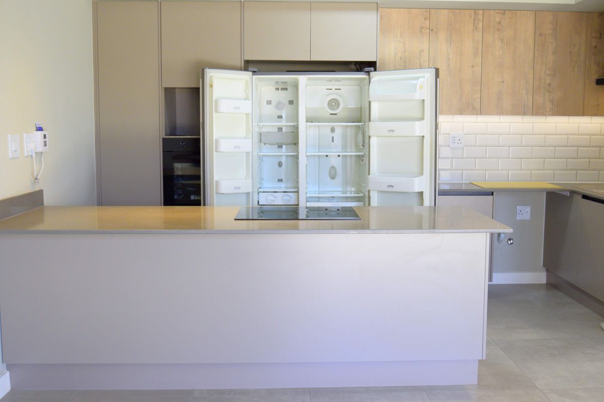 Modern kitchen featuring a central island with induction hob, quartz countertops, subway tile backsplash, and integrated cabinetry with a built-in oven.