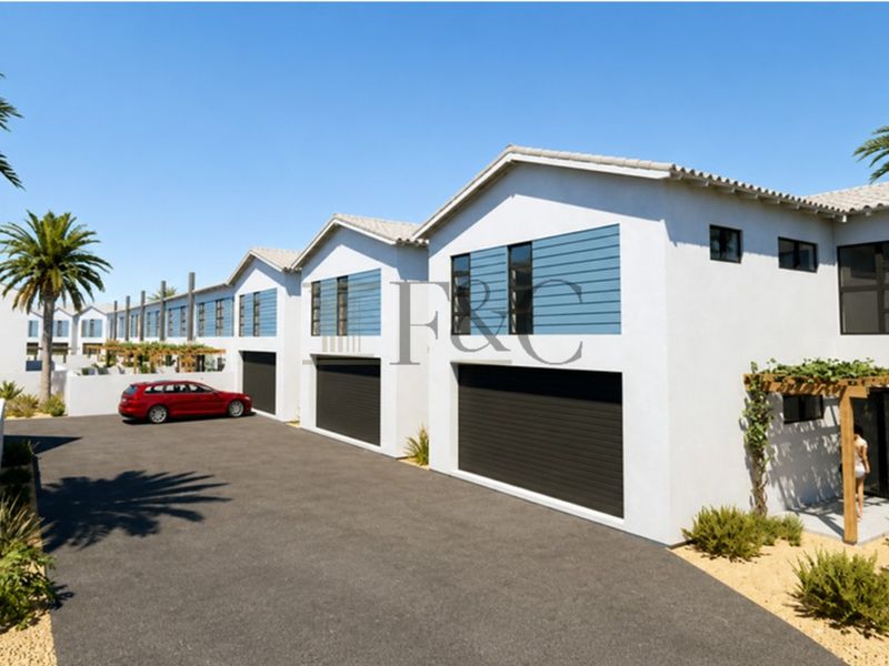 Modern townhouse complex featuring a clean white facade, dark sectional garage doors, and paved driveway access with integrated timber pergola structures.
