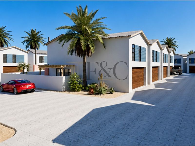 A modern townhouse complex featuring a paved driveway, multiple garage access points, and clean architectural lines in a well-maintained residential setting.