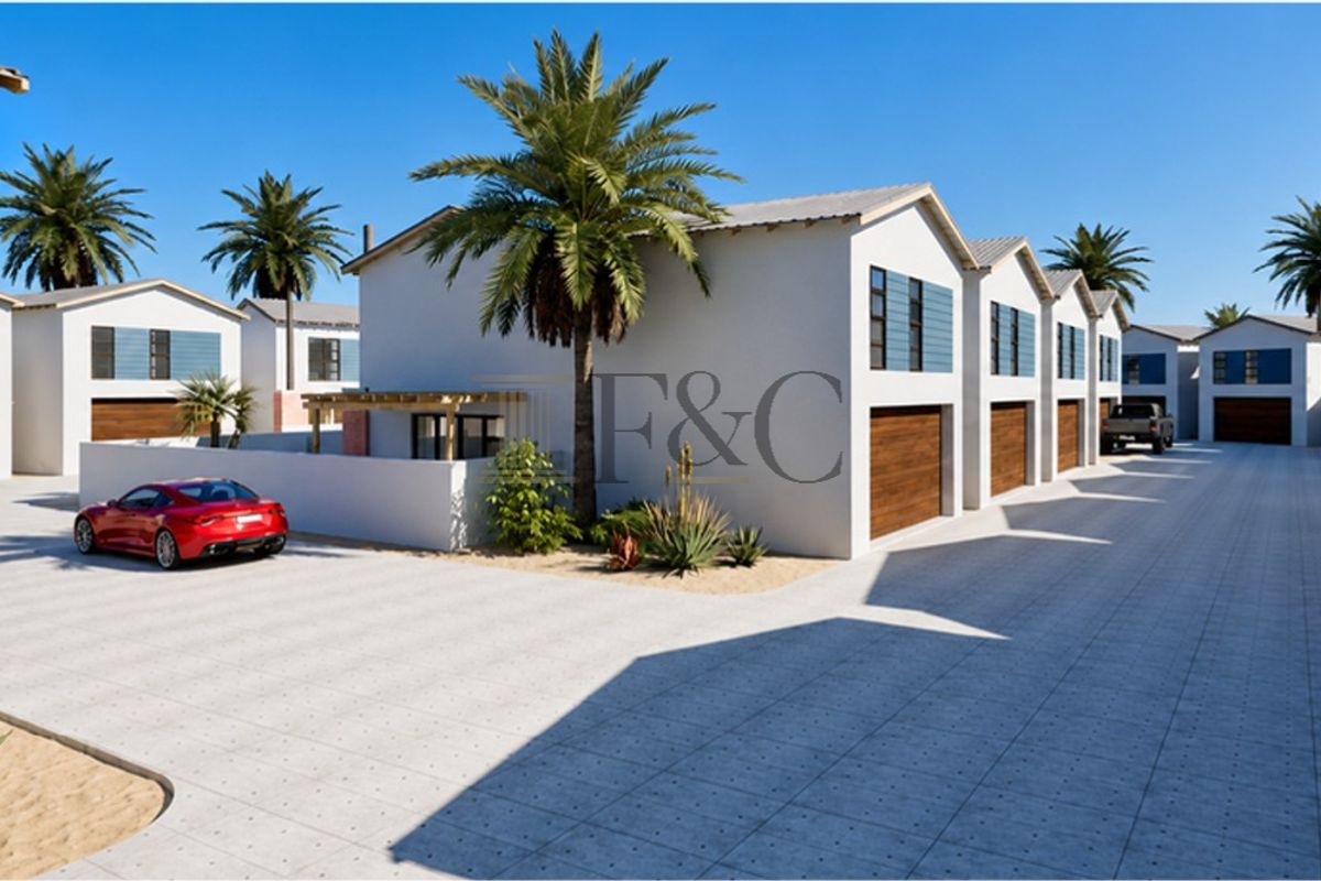 A modern townhouse complex featuring a paved driveway, multiple garage access points, and clean architectural lines in a well-maintained residential setting.