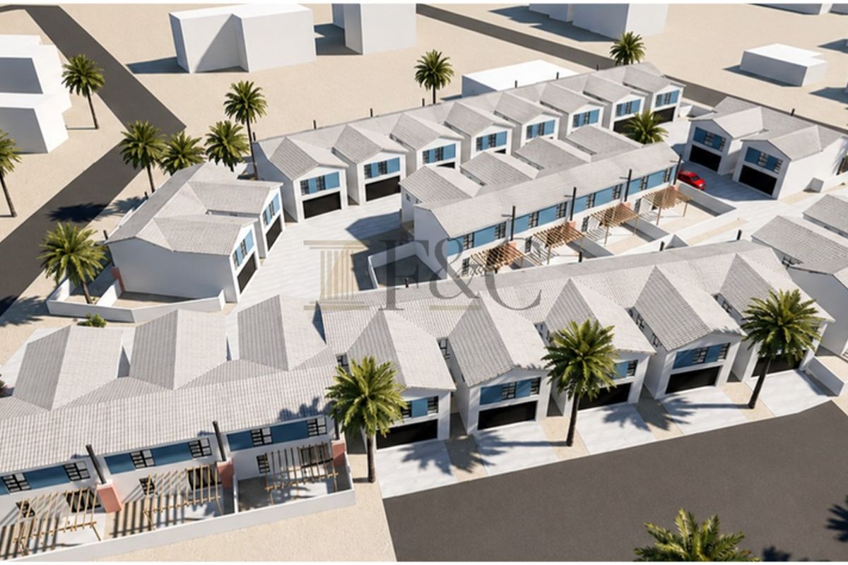 Aerial perspective of a modern townhouse development featuring multiple units with pitched roofs, integrated garages, and paved outdoor areas.