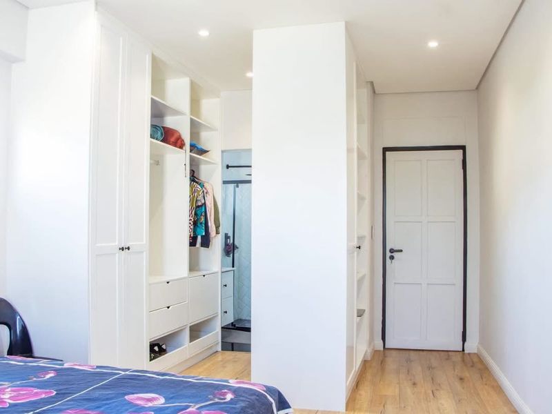 A well-maintained bedroom featuring extensive built-in cabinetry, recessed lighting, and modern laminate flooring, with an integrated walk-through closet area.