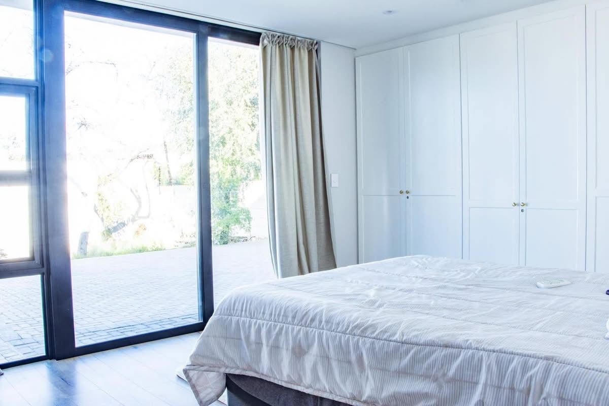 A bright bedroom featuring floor-to-ceiling built-in cupboards and a large sliding glass door providing direct access to the outdoor patio area.