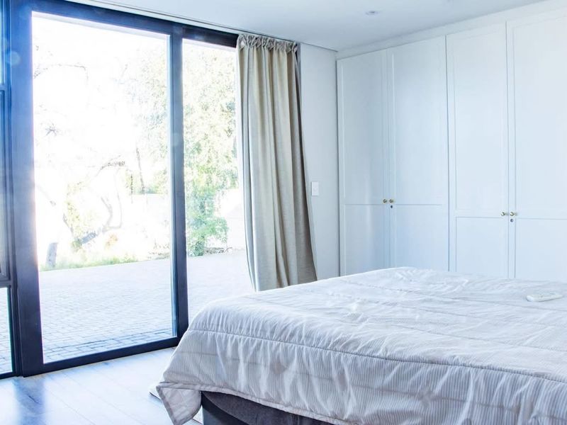 A bright bedroom featuring floor-to-ceiling built-in cupboards and a large sliding glass door providing direct access to the outdoor patio area.
