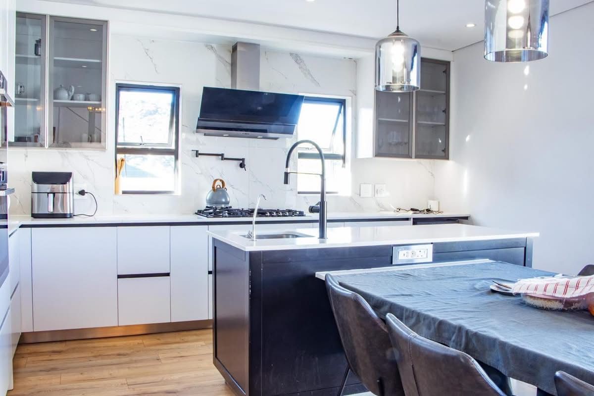 Modern kitchen featuring a central island, marble-look splashback, gas hob, extractor fan, and high-quality cabinetry with integrated lighting.