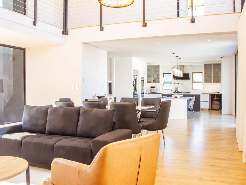 Spacious open-plan living and dining area featuring a modern kitchen with a central island, high ceilings, and contemporary finishes throughout.