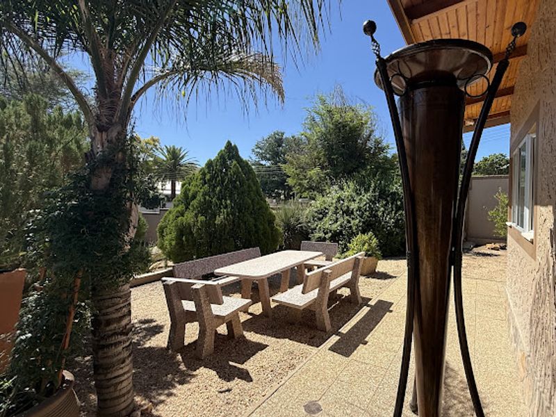 A covered outdoor patio area featuring stone paving and a timber ceiling, providing a functional space for outdoor relaxation and dining.
