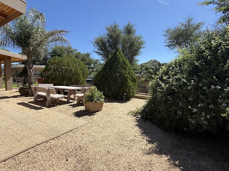 A sunny outdoor patio area featuring paved flooring and gravel landscaping, providing a pleasant space for outdoor relaxation.