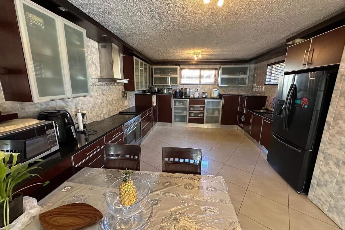 Spacious kitchen featuring dark wood cabinetry, granite countertops, stainless steel appliances, and tiled flooring throughout.