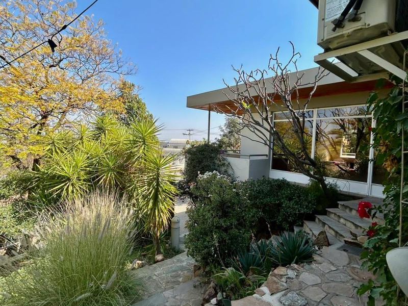 A landscaped rear garden area featuring stone-paved stairs leading to a patio with sliding glass doors and an exterior air conditioning unit.