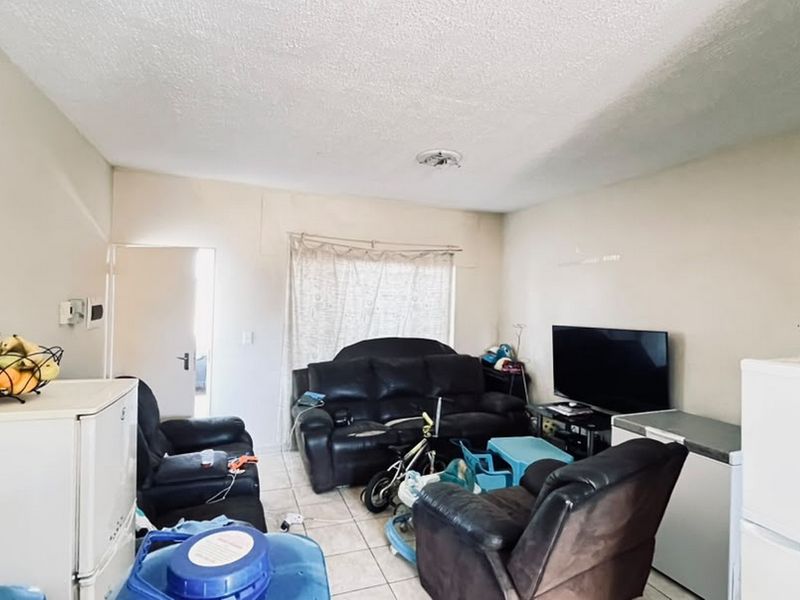 A living room area featuring tiled flooring and standard wall finishes, currently used as a multi-purpose living space.