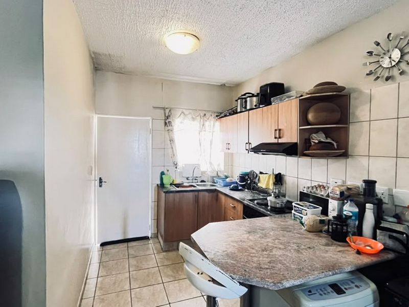 Compact kitchen featuring laminate cabinetry, tiled backsplash, and a breakfast nook. The space requires maintenance due to visible ceiling water damage.