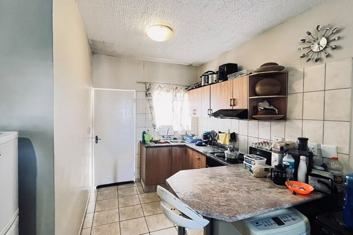 Compact kitchen featuring laminate cabinetry, tiled backsplash, and a breakfast nook. The space requires maintenance due to visible ceiling water damage.