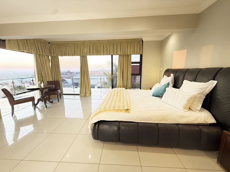 Spacious bedroom featuring large sliding glass doors that open to a balcony with expansive views, complemented by polished tile flooring and coved ceilings.