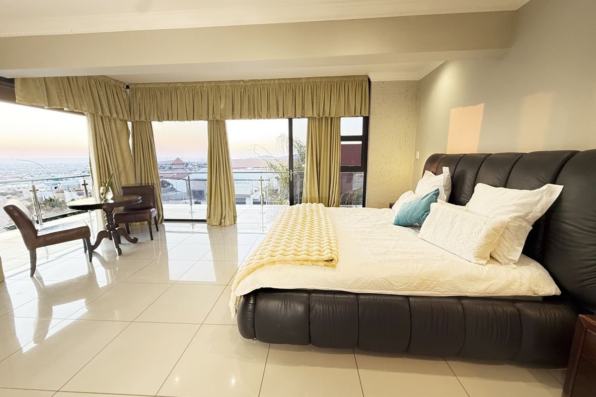 Spacious bedroom featuring large sliding glass doors that open to a balcony with expansive views, complemented by polished tile flooring and coved ceilings.